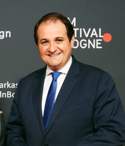 Medienminister Nathanael Liminski steht beim Film Festival Cologne vor eine Wand mit Logos. 