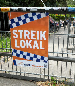 Ein Zaun mit einem Orangen Plakat, darauf der weiße Schriftzug: Streiklokal