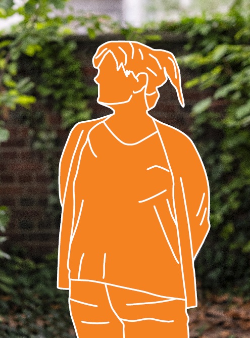 Eine Frau steht mit hinterm Rücken verschränkten Armen vor einem Busch. Zur Anonymisierung ist ihr Körper mit einer orangen Fläche und weißen Konturen abgedeckt. 