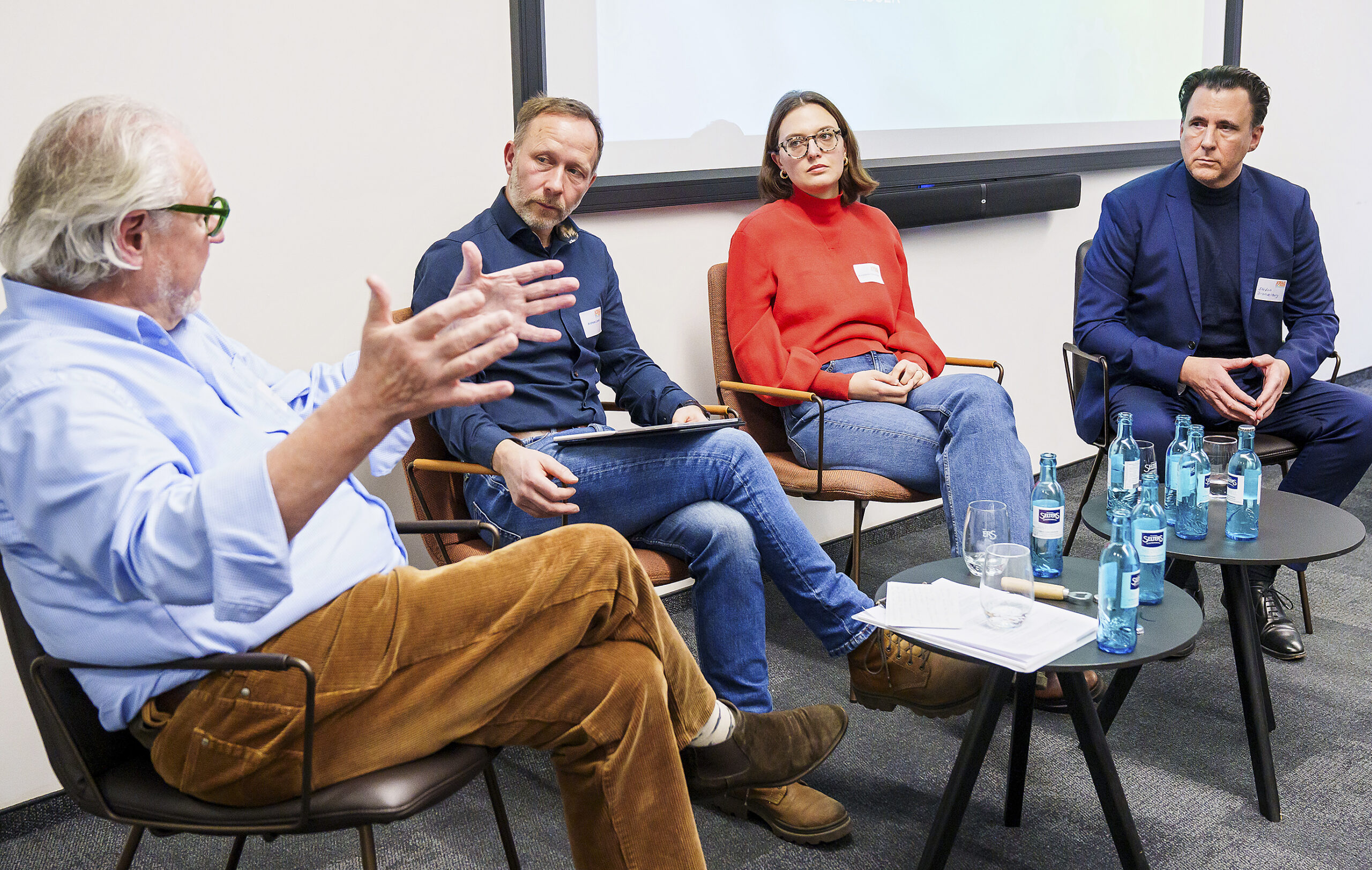 Ein vierköpfiges Podium von der Seite her fortorgarfiert. Zu sehen sind drei Männer und eine Frau.