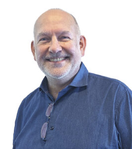 Ein Mann lächelt in die Kamera. Er trägt ein blaues Hemd