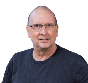 Ein Mann mit sehr kurzen Haaren und Brille, der freundlich lächelt. Er trägt einen dunklen Pulli.