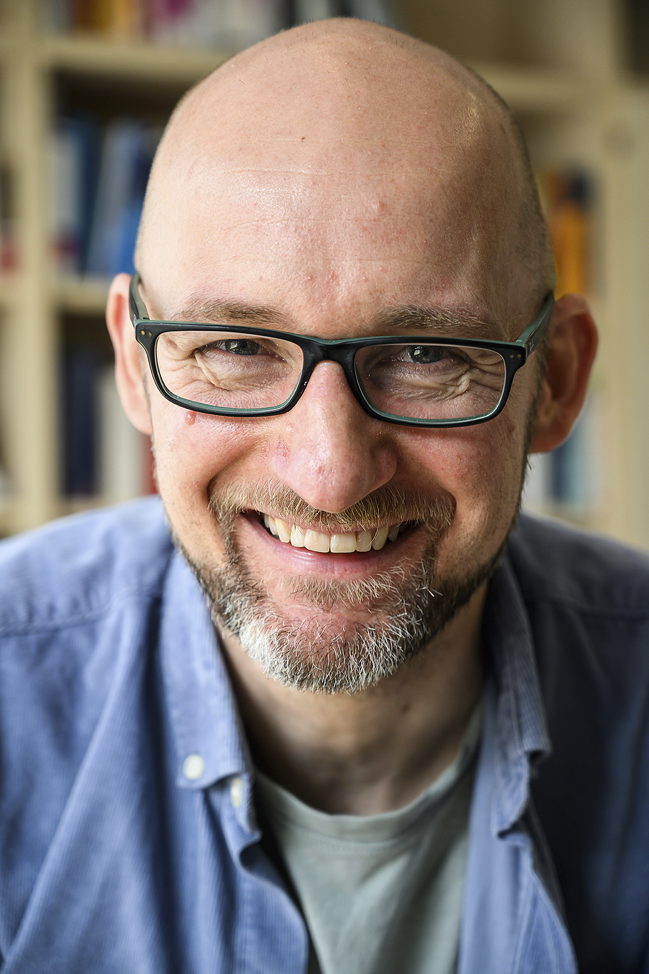 Ein Mann mit Brille und Bart lacht in die Kamera.